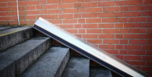 Metallene Fahrradschiene, montiert an einer Backsteinmauer entlang einer Betontreppe