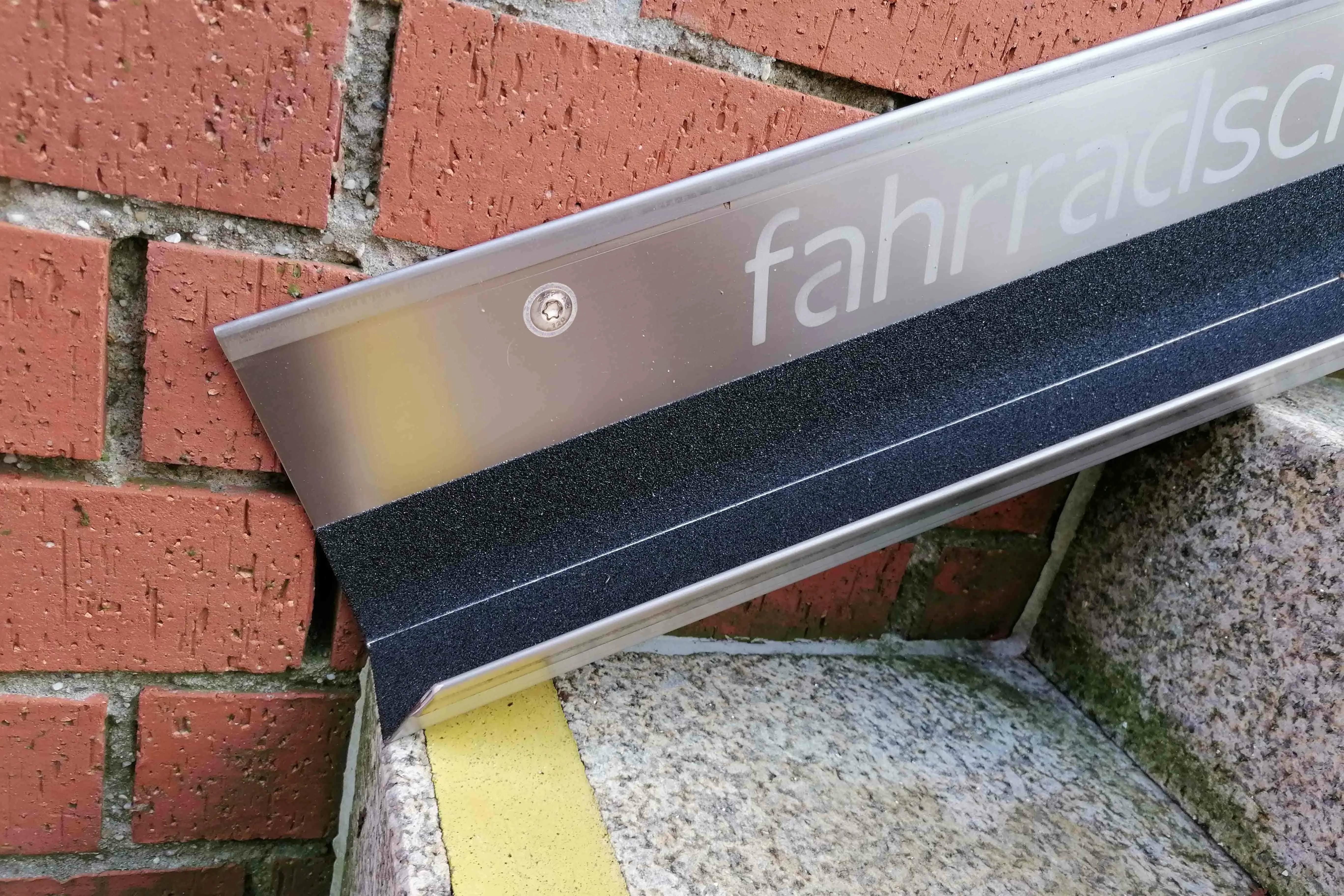 Fahrradschiene aus Metall, befestigt an einer Außentreppe mit gelber Markierung
