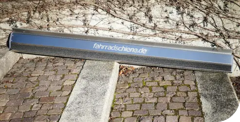 Silberne Fahrradschiene mit der Aufschrift fahrradschiene.de, platziert auf einer Steintreppe